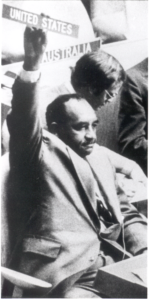 Clarence Mitchell, Jr. an African Americanman in a suit, holds up a sign reading "United States" 