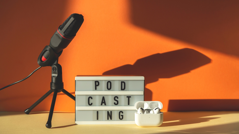image of a microphone next to a board that says Podcasting and earbuds